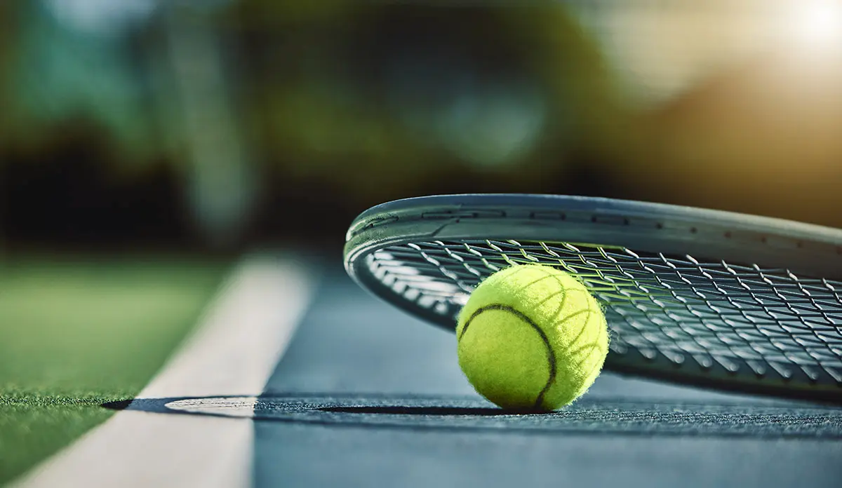 photo of Tennis ball and racquet on court